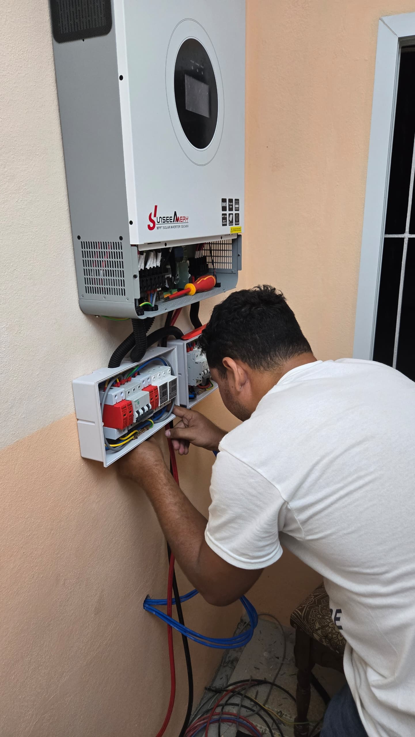 Técnico trabajando en el cableado y las protecciones de un inversor solar